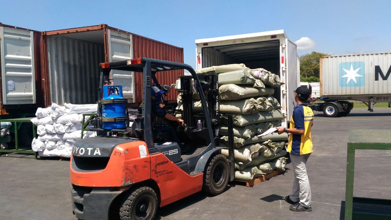 Forklift memuat barang ke truk box di area pelabuhan/gudang